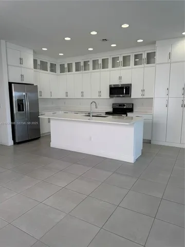 a large kitchen with stainless steel appliances kitchen island granite countertop a large stove a sink a microwave and a refrigerator