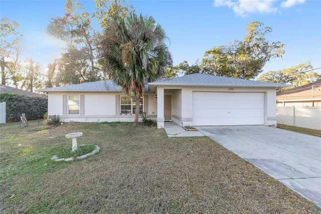 a front view of house with yard and trees in the background