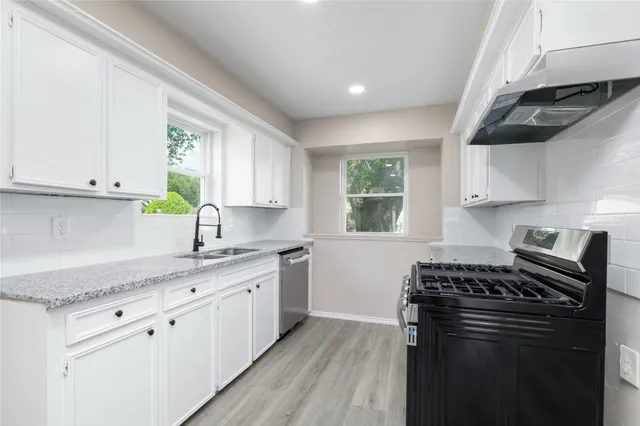 a kitchen with granite countertop a sink cabinets stainless steel appliances and a window
