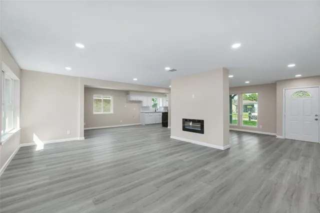 an empty room with wooden floor fireplace and windows