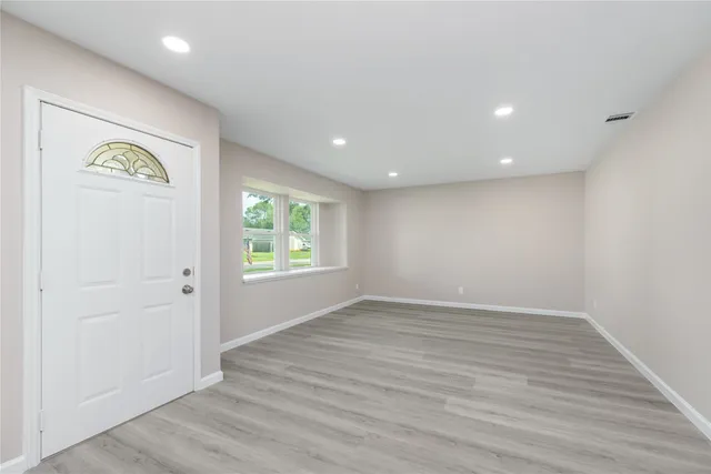 an empty room with wooden floor and window