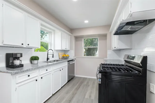 a kitchen with stainless steel appliances a sink a stove and cabinets