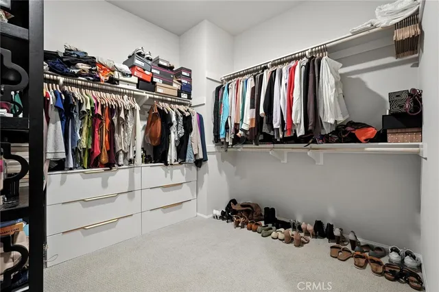 a view of walk in closet with clothes and shoes
