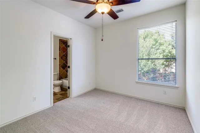 an empty room with chandelier fan and windows