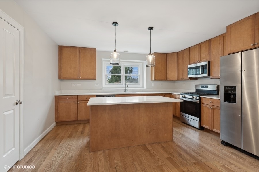 452 Mildred Avenue Cary, IL 60013 - Photo 6 of 20 a kitchen with stainless steel appliances granite countertop a stove a sink and a refrigerator with wooden floors