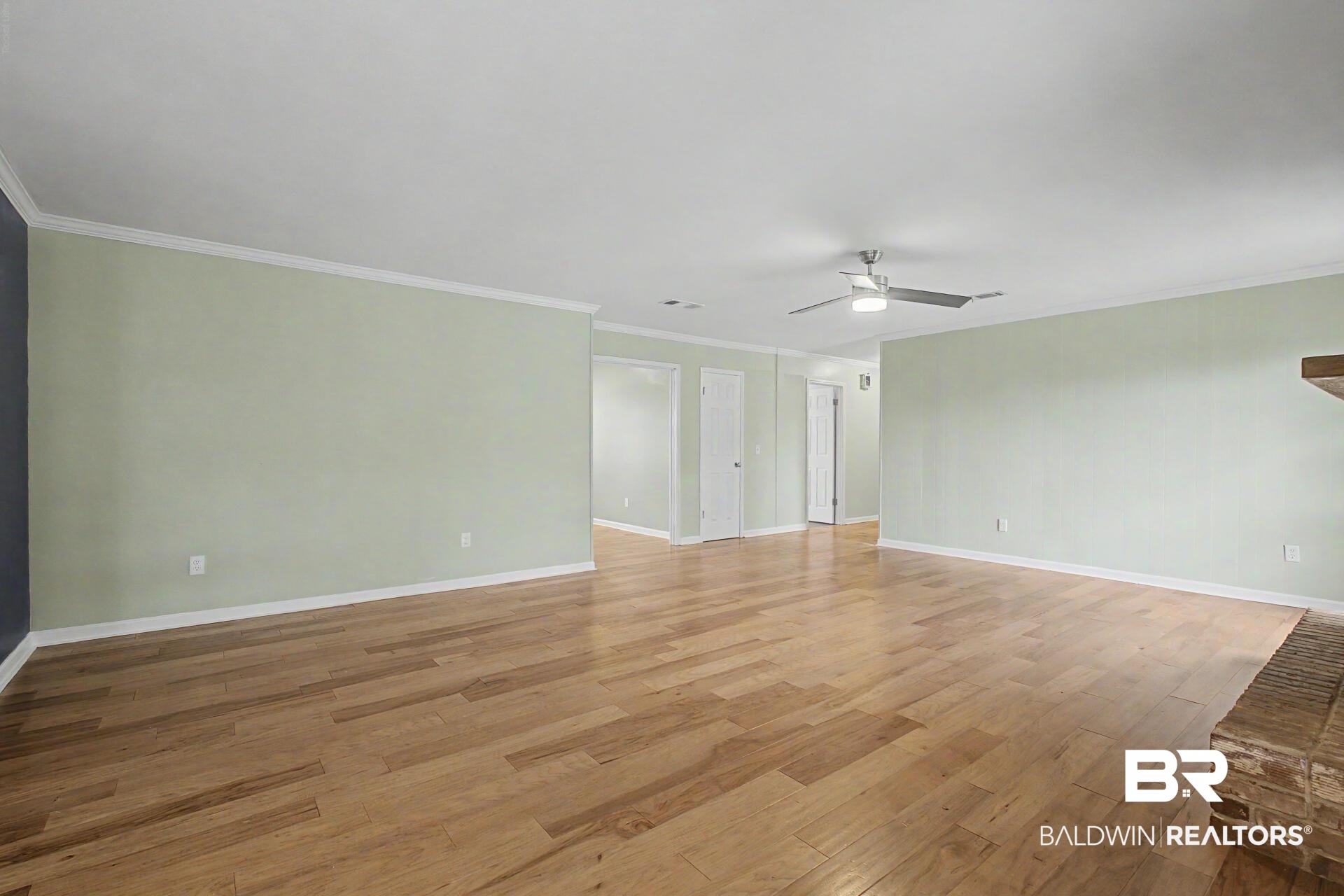 3791 Robinsonville Road Atmore, AL 36502 - Photo 30 of 47 Expansive living area featuring light wood-finish flooring, a contemporary ceiling fan with integrated lighting, and crown molding accents
