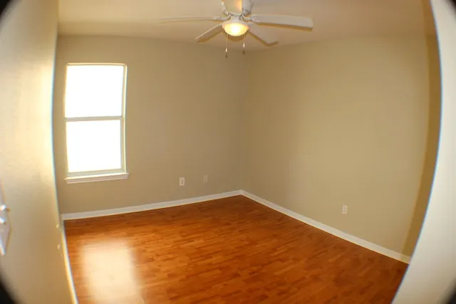 an empty room with a window and chandelier fan