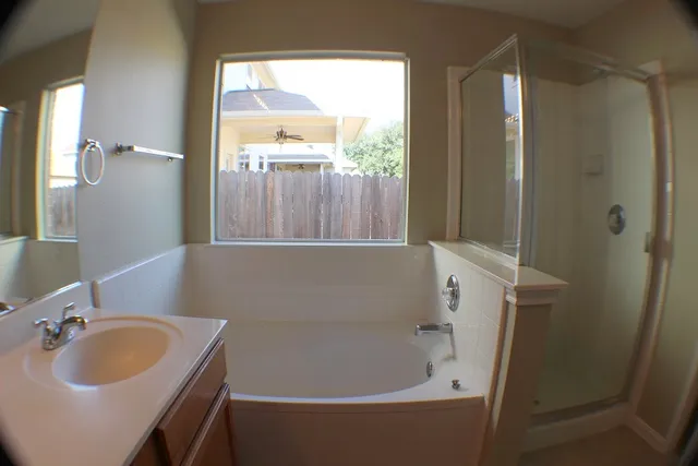 a bathroom with a tub a sink and a window