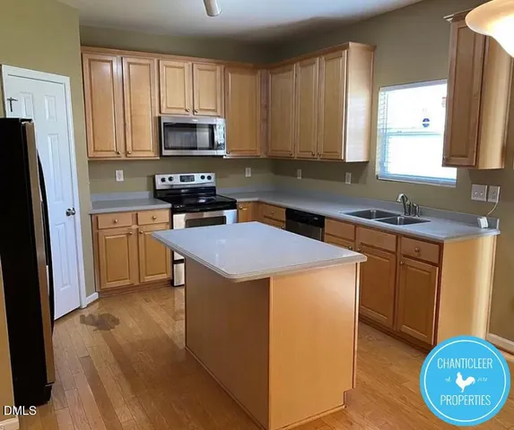 a kitchen with a sink a stove a microwave a refrigerator a counter space and cabinets