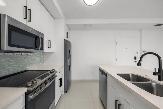 a kitchen with stainless steel appliances a sink a stove a microwave and cabinets