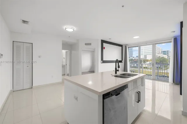 a view of a kitchen island a sink dishwasher and wooden cabinets