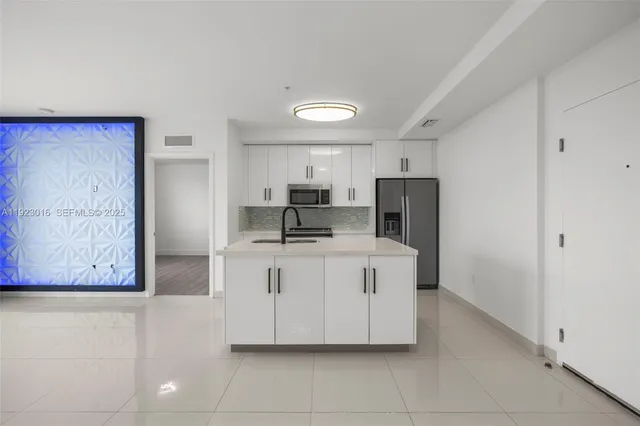 a large white kitchen with a sink a refrigerator and a stove top oven
