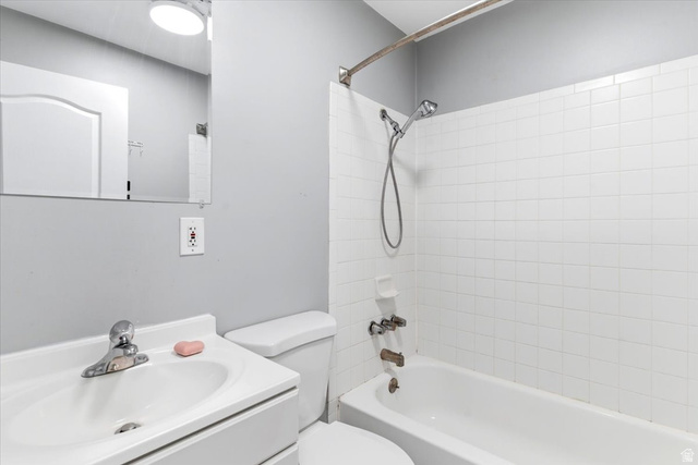 1613 Sunset Road Lake Point, UT 84074 - Photo 16 of 33 Bathroom featuring a vanity with an integrated sink, a commode, a shower/tub combination with white subway tile surround, and a wall-mounted mirror