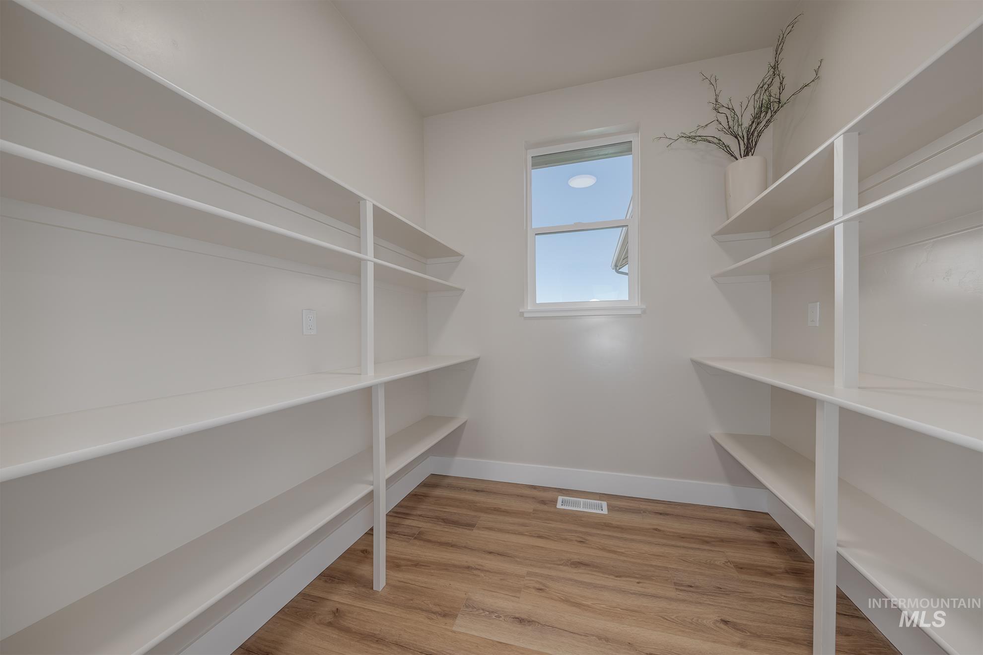 1371 Hansen Road Weiser, ID 83672 - Photo 17 of 44 Expansive pantry featuring extensive built-in shelving, wood-finish flooring, and a window