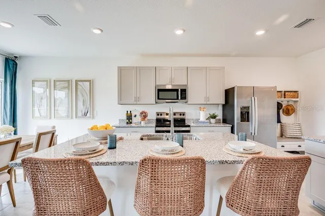 a kitchen with stainless steel appliances granite countertop a refrigerator a stove a sink dishwasher a dining table and chairs with wooden floor