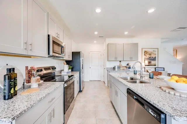 a large kitchen with stainless steel appliances granite countertop a sink stove and refrigerator