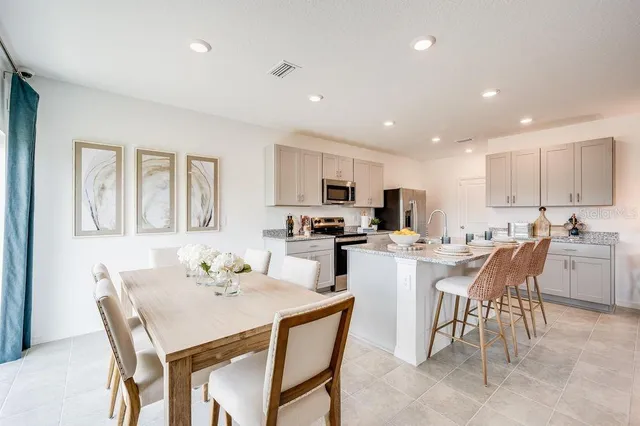 a kitchen with a dining table chairs and refrigerator