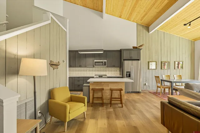 a living room with a table chairs and a kitchen view
