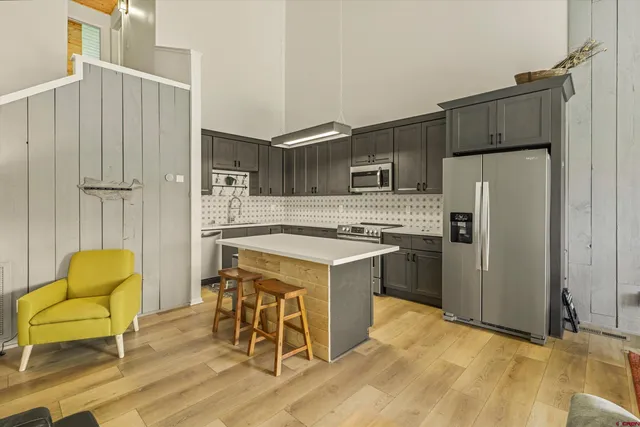 a kitchen with stainless steel appliances a stove a refrigerator and a couch