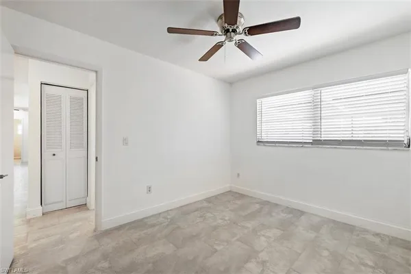an empty room with a window and a fan