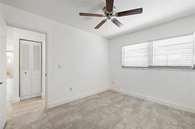 an empty room with a window and a fan