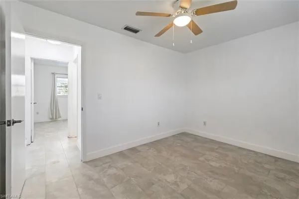 an empty room with a ceiling fan and a window