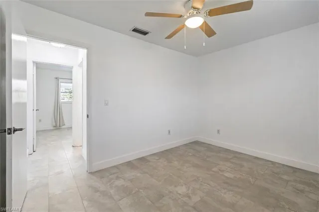an empty room with a ceiling fan and a window
