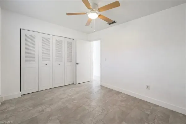 an empty room with closet and a ceiling fan