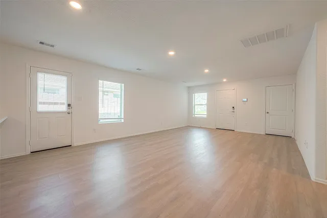 an empty room with wooden floor and windows
