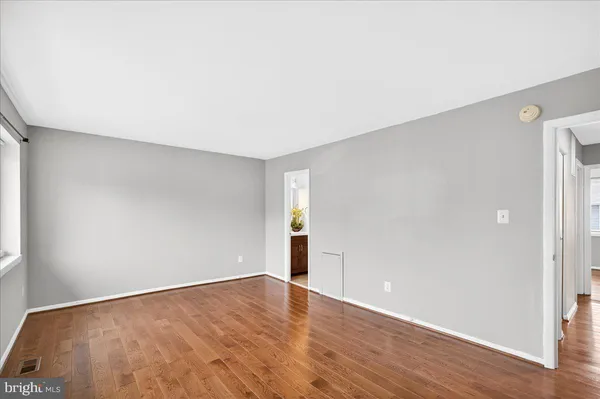 a view of an empty room with wooden floor and closet