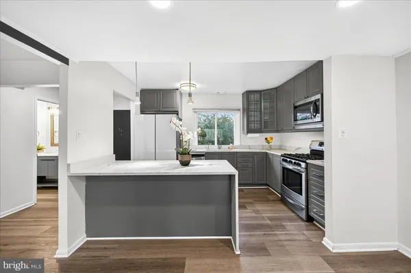 a kitchen with stainless steel appliances kitchen island granite countertop a stove refrigerator and cabinets