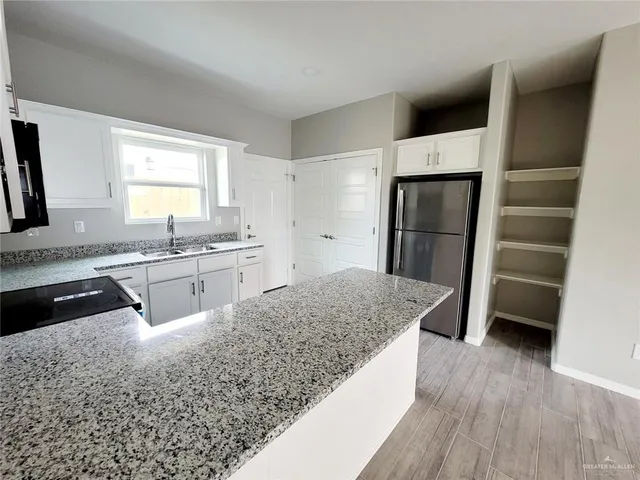 a view of a kitchen with a sink and dishwasher a refrigerator with wooden floor