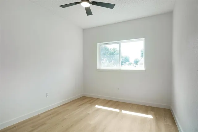an empty room with a window and a fan