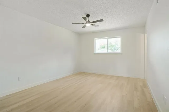 an empty room with windows and fan