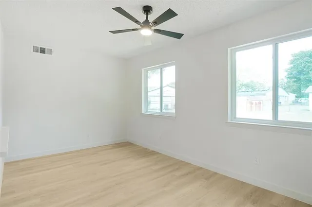 an empty room with a window and a fan