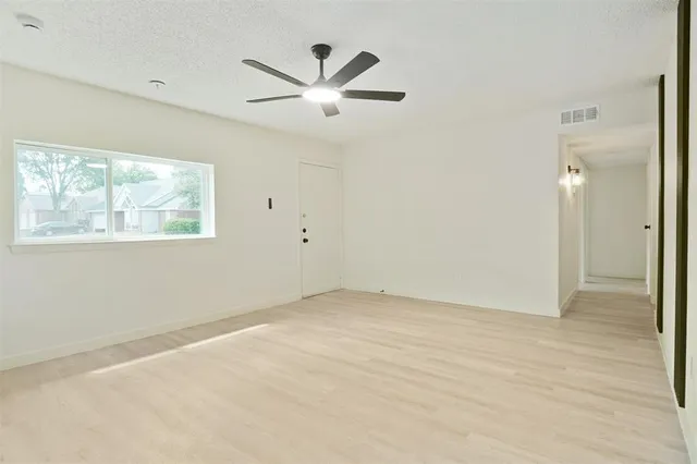 a view of an empty room with wooden floor and window