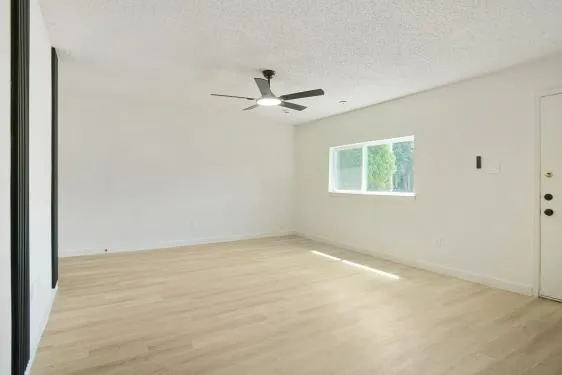 an empty room with a window and a ceiling fan