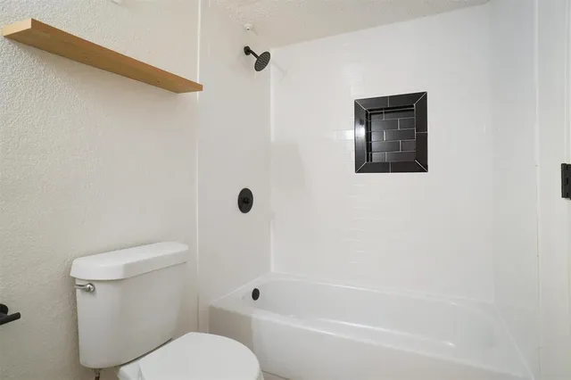 a white toilet sitting next to a bath tub