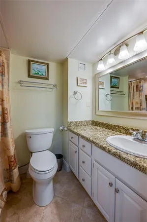 a bathroom with a granite countertop toilet sink and mirror