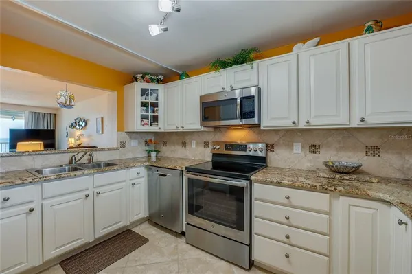 a kitchen with stainless steel appliances granite countertop a sink and dishwasher a stove top oven with white countertops