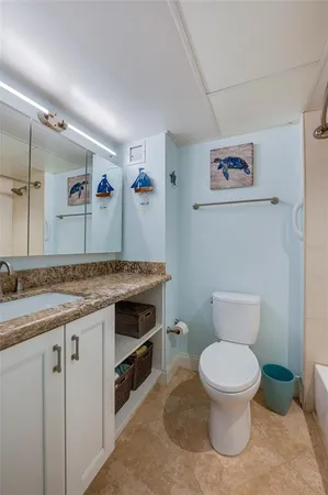a bathroom with a granite countertop toilet sink and mirror