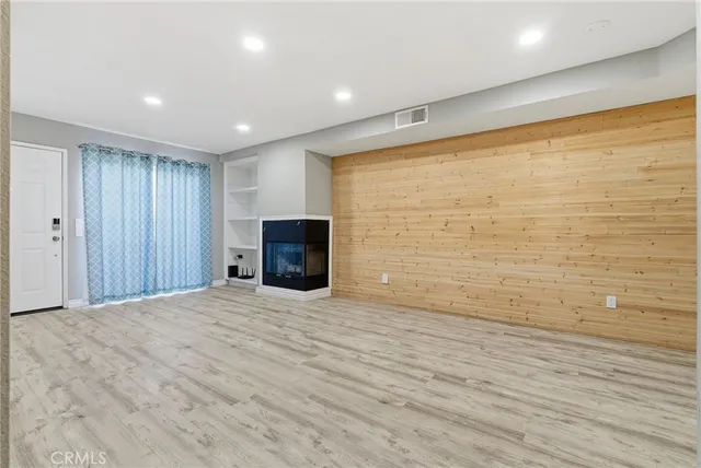 a view of empty room with wooden floor and fireplace
