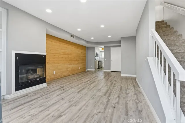 a view of an empty room with wooden floor and a fireplace