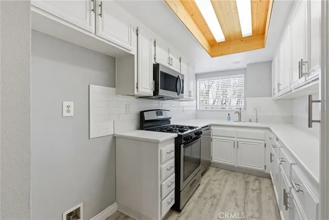 a kitchen with stainless steel appliances granite countertop a stove a sink and a microwave