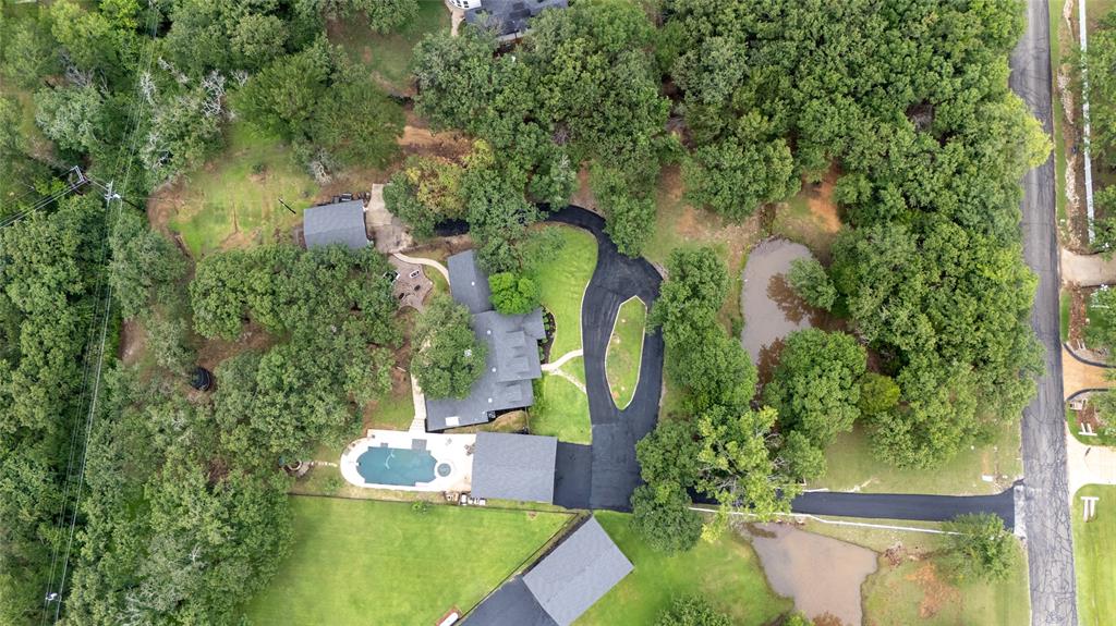 8948 David Fort Road Argyle, TX 76226 - Photo 5 of 39 Aerial view showcasing a residential property with established trees, a main residence with a dark-toned roof, a detached structure with a matching roof, a swimming pool with surrounding patio space, and a curved asphalt driveway
