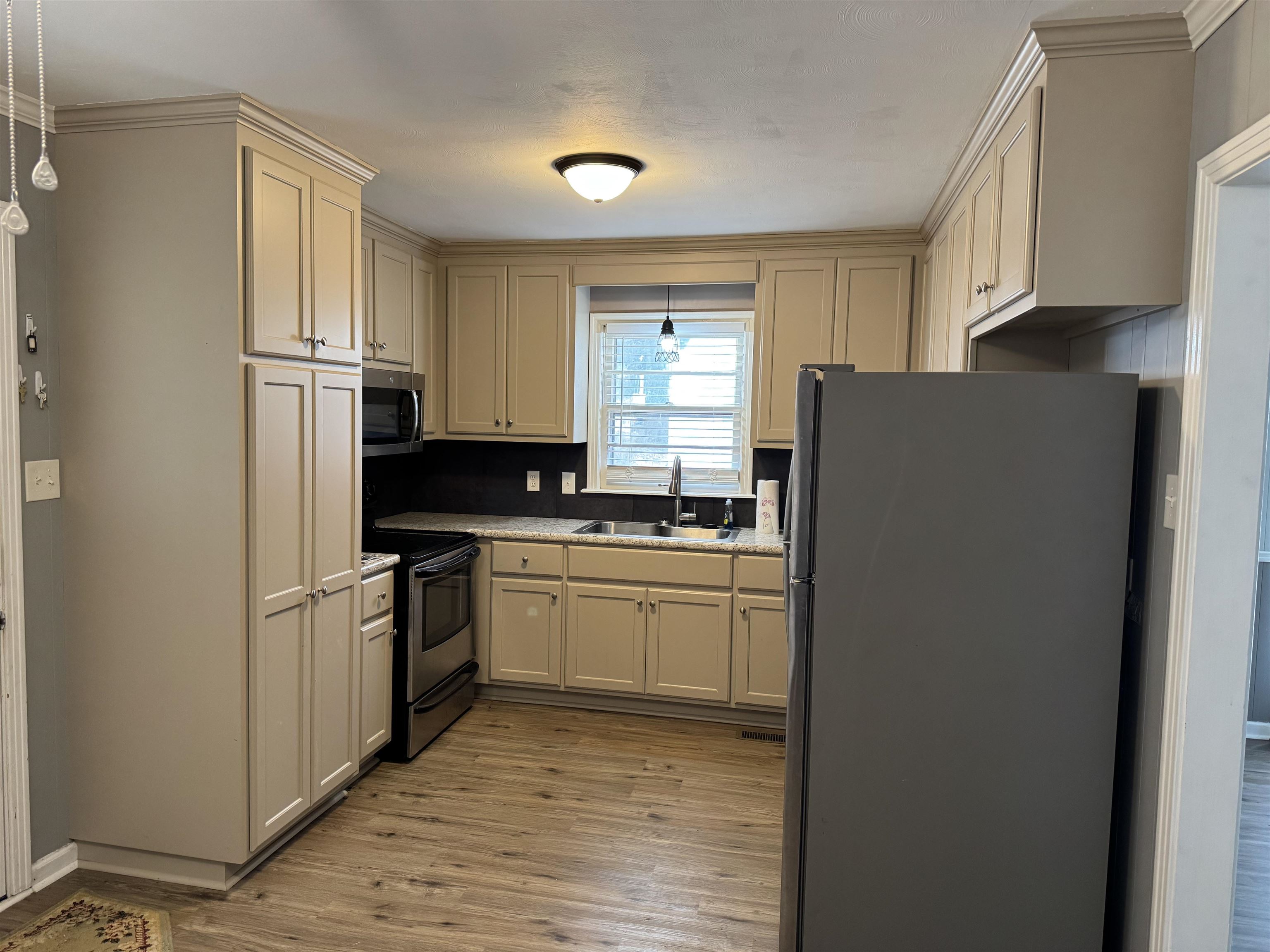 258 Church Street Ripley, TN 38063 - Photo 13 of 25 Kitchen featuring sink, hanging light fixtures, stainless steel appliances, light wood-type flooring, and cream cabinetry
