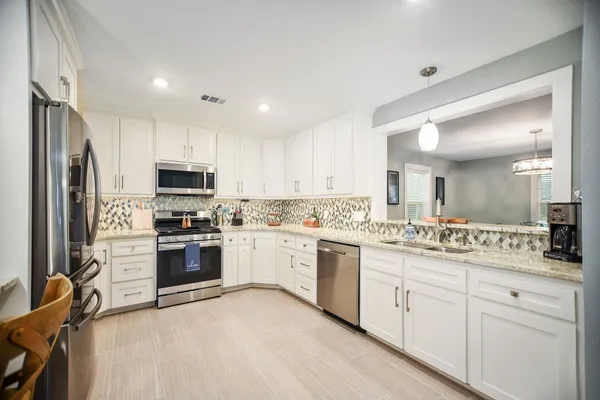 a kitchen with granite countertop white cabinets and stainless steel appliances