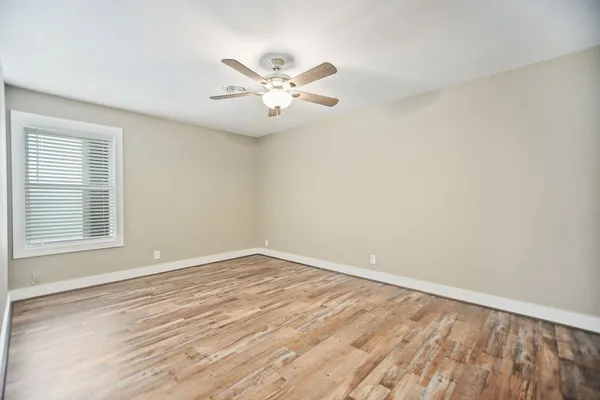 a view of an empty room with wooden floor and a window