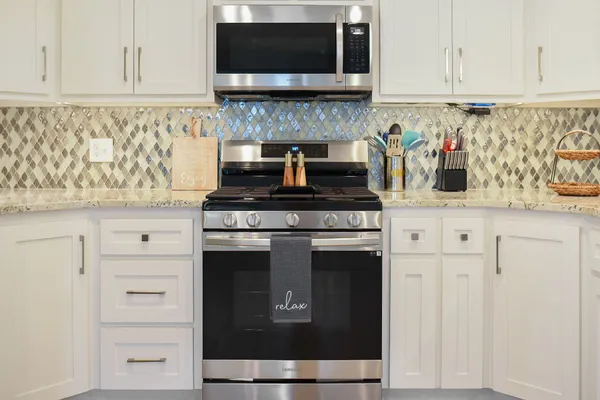 a kitchen with granite countertop white cabinets and stainless steel appliances