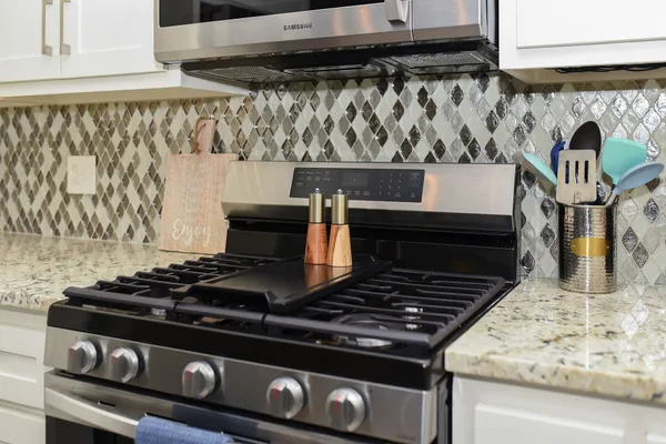 a stove sitting inside of a kitchen with white cabinets